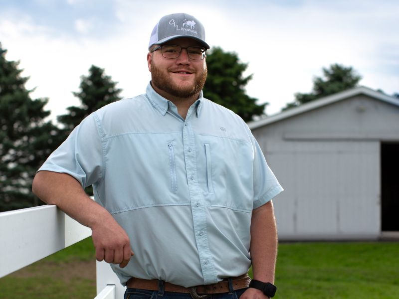 Logan standing alongside fenced farm