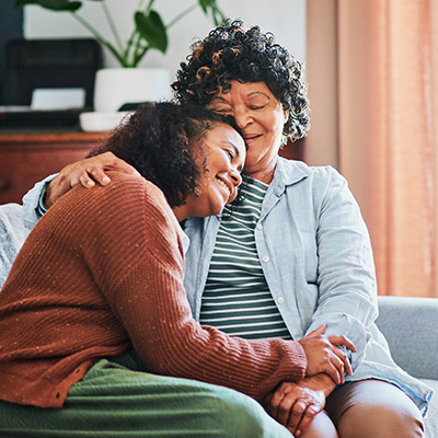 Younger woman smiling and leaning on older woman smiling