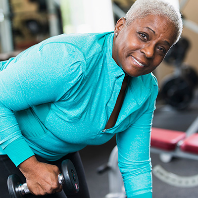 Woman wearing blue top and lifting a weight