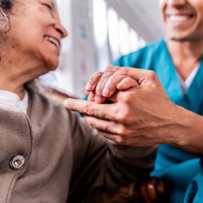 Older woman and clinical staff holding hands