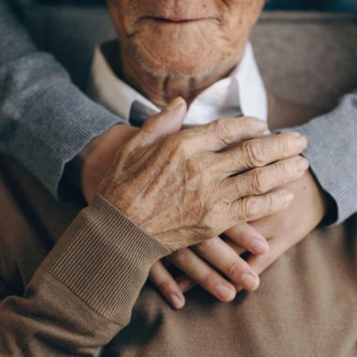 Hands hugging an older man