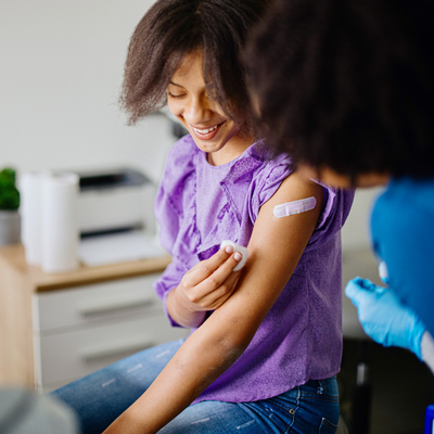 Teen girl getting her HPV vaccine at doctor's office while accompanied by her mother