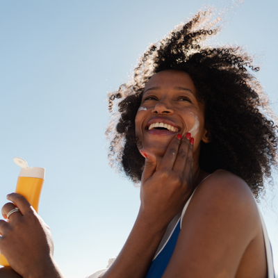 African American woman applying sunscreen at the beach