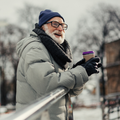 Happy bearded senior man in green coat smiling and looking away