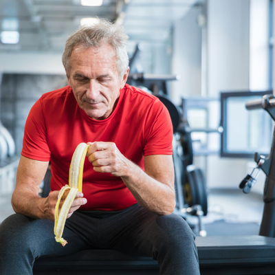 older man eating a banana in a gym