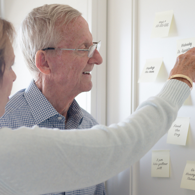 Elderly couple pointing and looking at sticky notes reminders