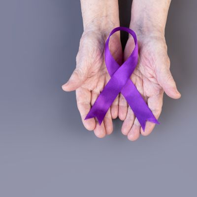 A person holding a purple ribbon in their hands for Alzheimer's awareness