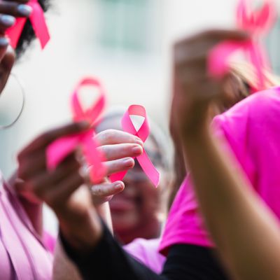 A group of people holding pink ribbons for breast cancer awareness