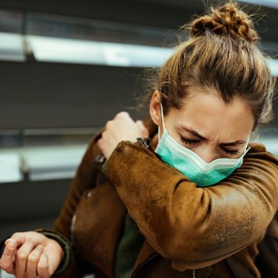 A woman with a mask on sneezing