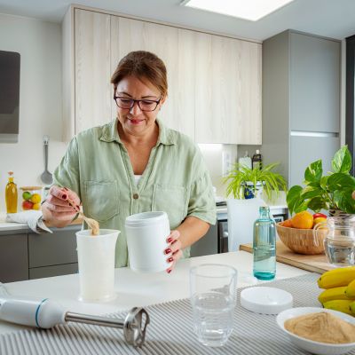 A woman preparing a protein drink in her kitchen