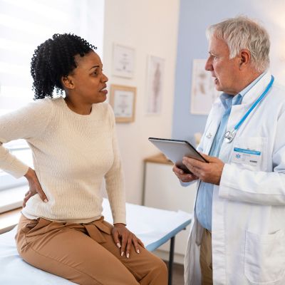 A woman with back pain talking to a doctor