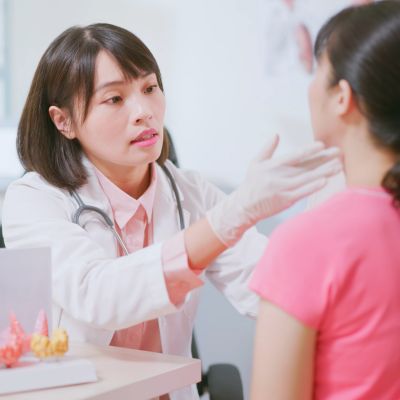 A doctor examining her patient's thyroid