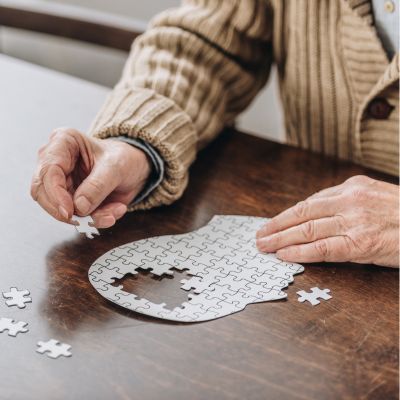 An older man putting together a puzzle of a brain
