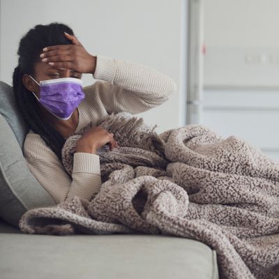 A woman with a mask on feeling unwell