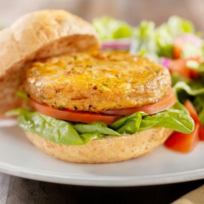 A veggie burger next to a salad on a plate