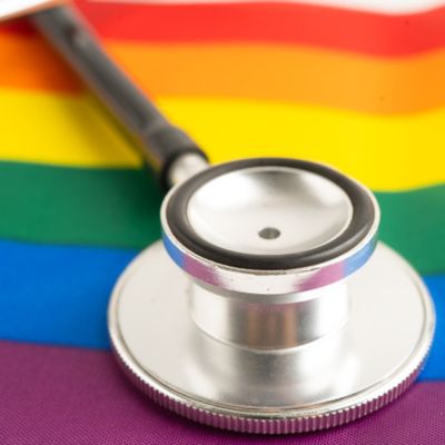 A stethoscope laying on top of a LGTBQ flag