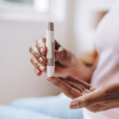 Woman pricking finger with lancing device