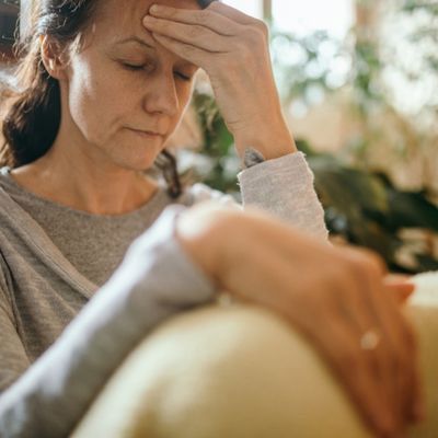 Woman sitting down with hand on forehead