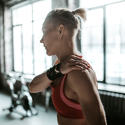 Woman in gym holding shoulder