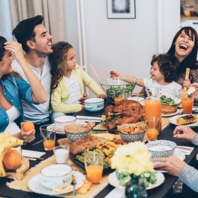A happy family sitting at a table eating a large meal.