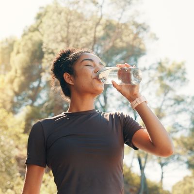 Woman drinking water while exercising outside