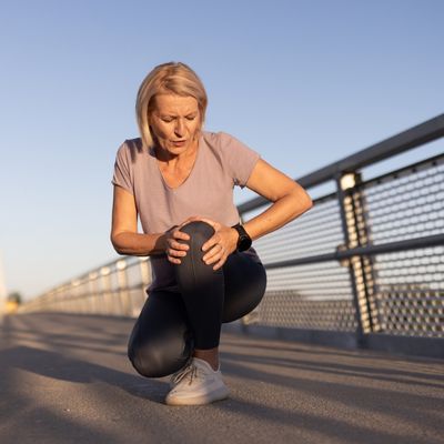 Woman outside holding knee in pain