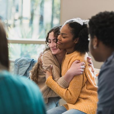 Two women embracing in a group therapy session