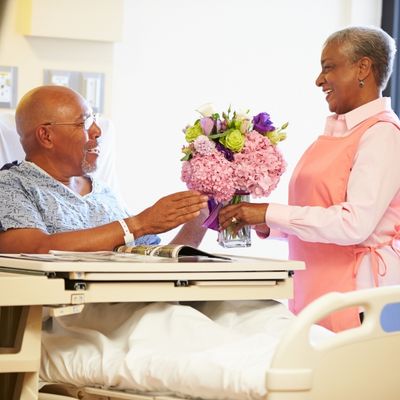 Volunteer bringing flowers to patient in hospital bed
