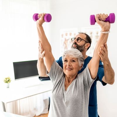 Older woman lifting weights with trainer