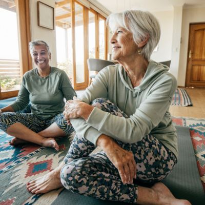 Two older woman doing floor stretches