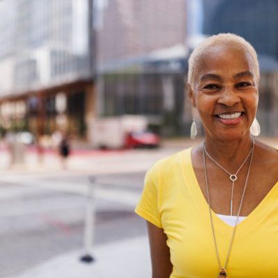 Older black lady in a yellow shirt in city