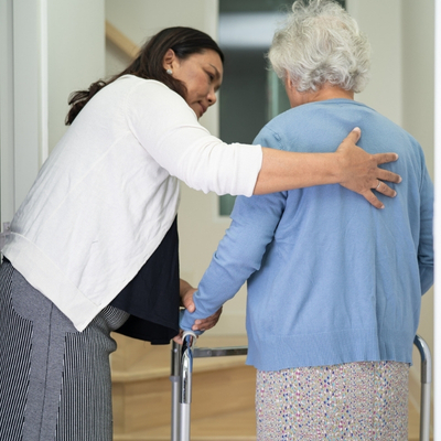 Family member helping older female adult with walker