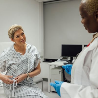 Woman in patient gown speaking with provider