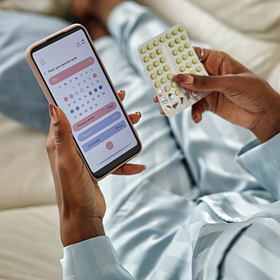 Woman with phone calendar and birth control