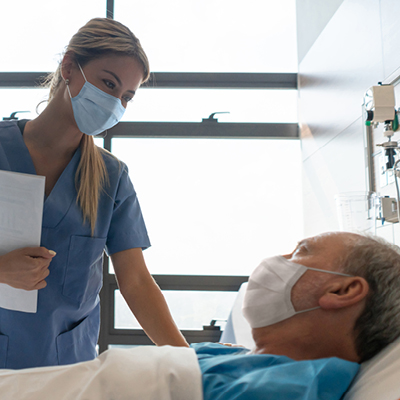 man laying in hospital with nurse checking on him