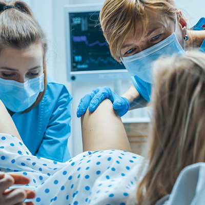 Doctors wearing masks while woman gives birth