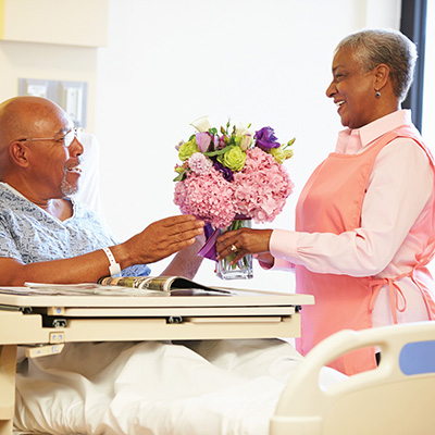 Woman giving man in hospital flowers