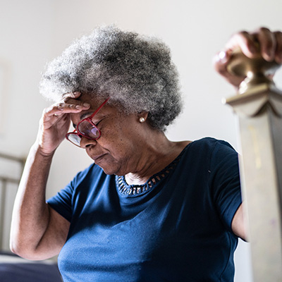 Woman holding her head and grabbing onto a post