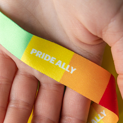 hand holding a rainbow band that says "Pride Ally"