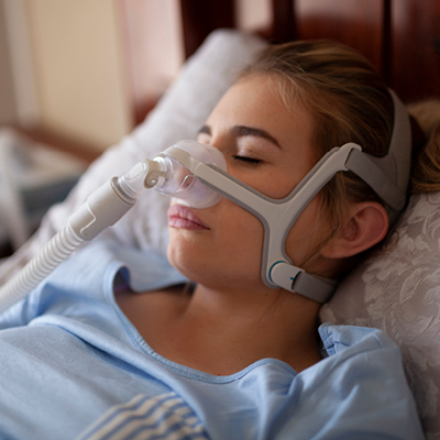 Women laying in bed with CPAP machine on her face