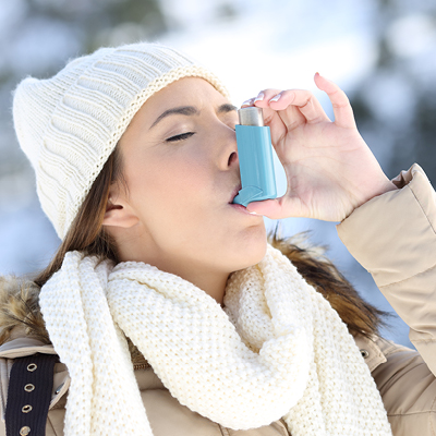 Woman using her inhaler in the winter 