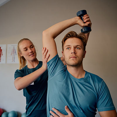 sports medicine doctor evaluating a male patients shoulder