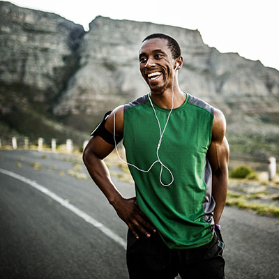 Running is more popular than ever Man wearing green tank listening to music post run