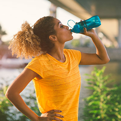 Nutrition and Hydration Women in yellow t-shirt drinking water