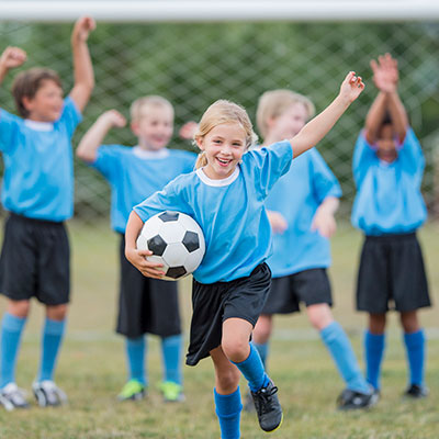 Child holding a soccer ball with friends in background