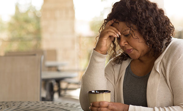 Woman stressed, holding a cup of coffee.