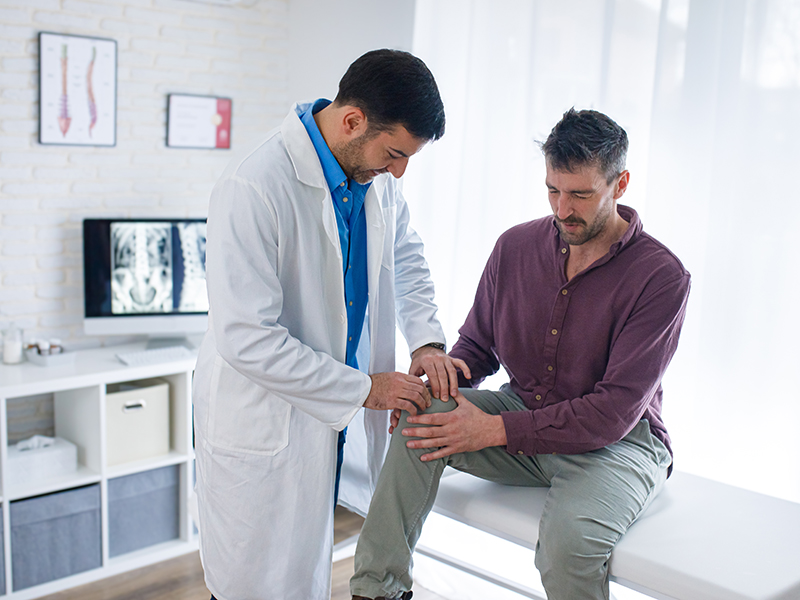 Male doctor looking over a male patient's knee
