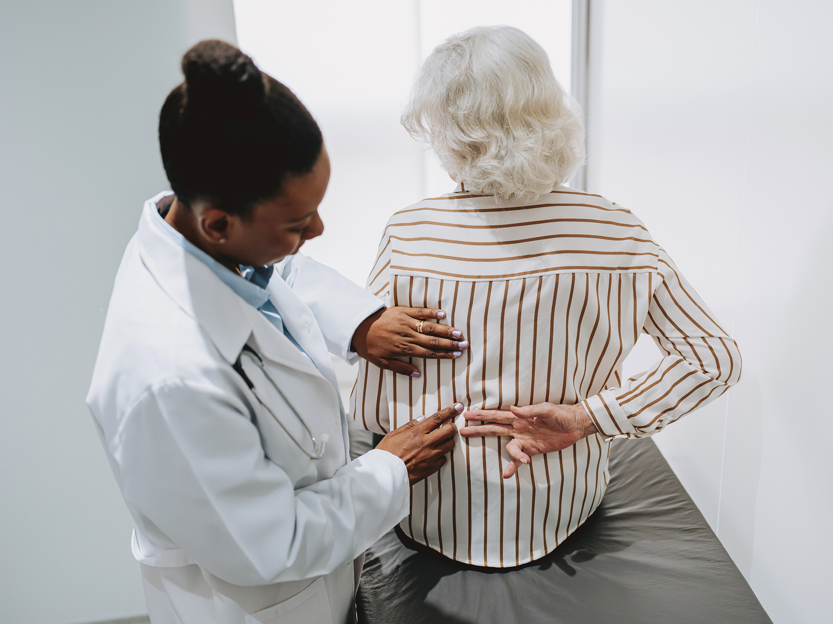 Doctor examining older lady's back 