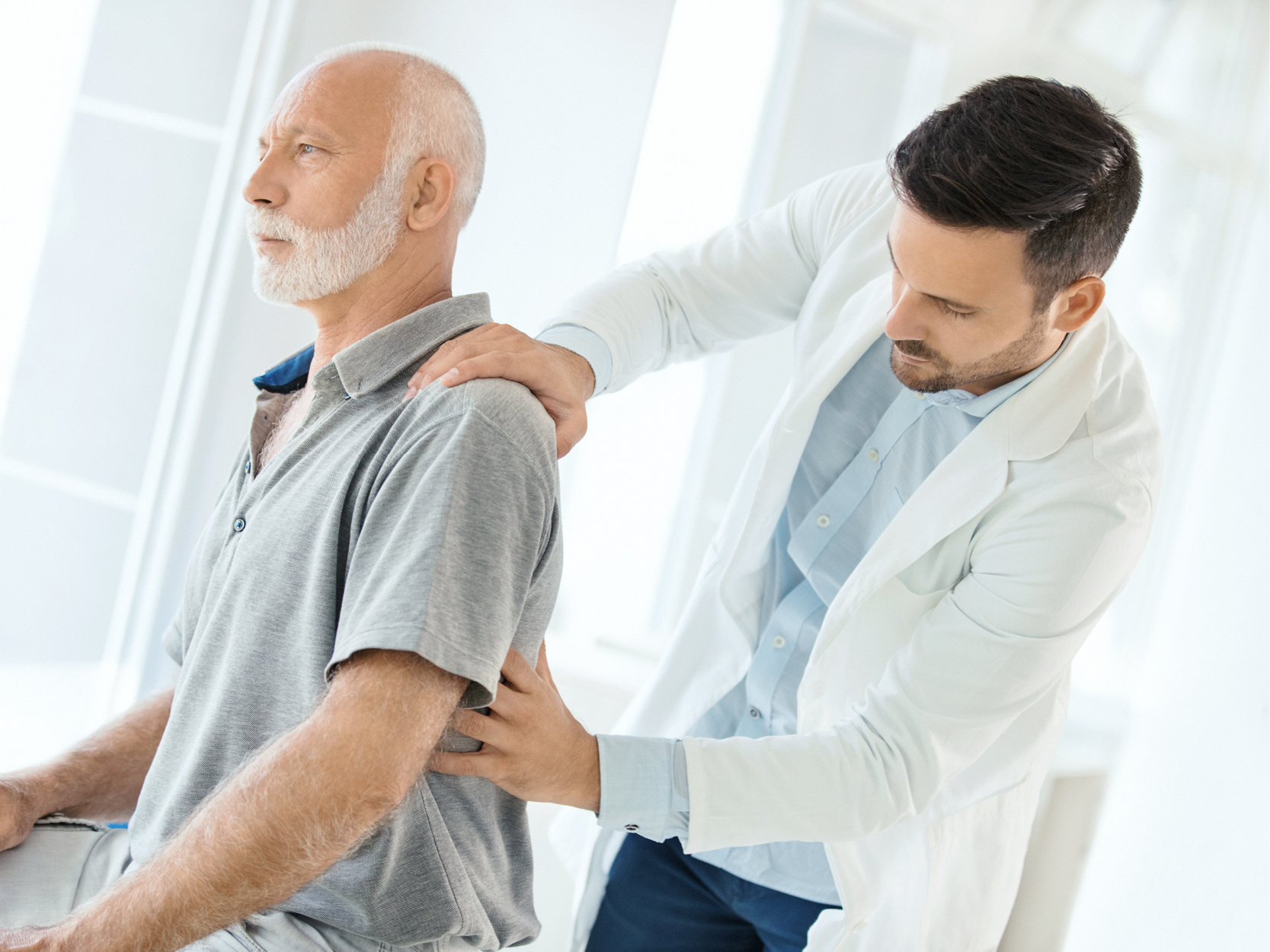 Older man getting his back checked by provider