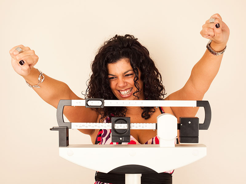 woman celebrating her weight loss on a scale